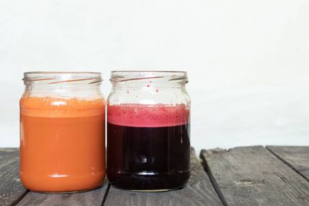 freshly squeezed carrot and beetroot juice in banks on a table in the morning