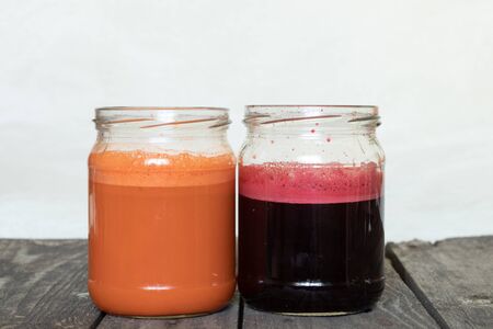 freshly squeezed carrot and beetroot juice in banks on a table in the morningの写真素材