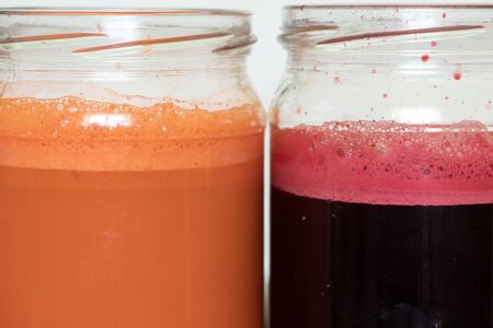 freshly squeezed carrot and beetroot juice in banks on a table in the morningの写真素材