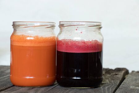 freshly squeezed carrot and beetroot juice in banks on a table in the morningの写真素材