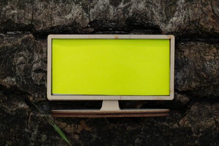 wooden small tv with a yellow screen stands on a tree in the forest, empty space for text