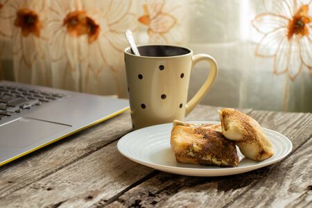 curd pancakes on a plate, a cup of tea and a laptop on a wooden tableの写真素材