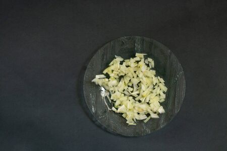 chopped raw onions in a plate on a black backgroundの写真素材