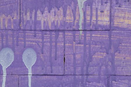 purple paint flows down a brick wallの写真素材