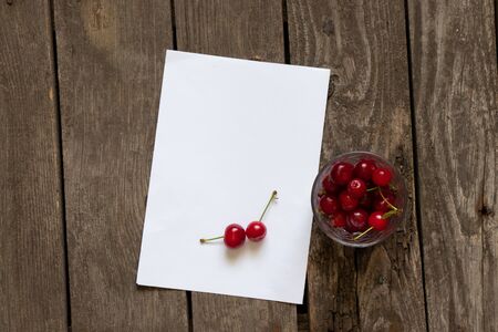 empty leaflet place for text and glass with cherries on an old tableの写真素材