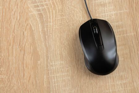 black wired computer mouse on a wooden table close-upの写真素材