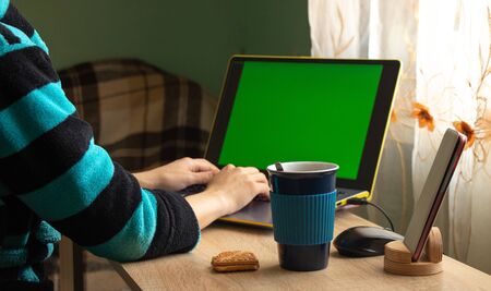 a girl sitting in quarantine works at a laptop in the room of her house