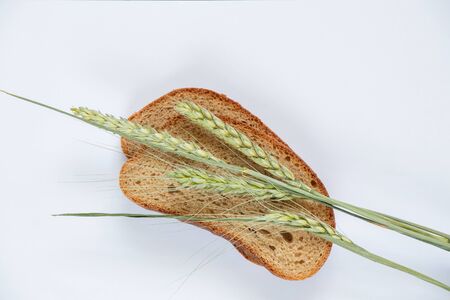 piece of black bread and ears of wheat on a whiteの写真素材