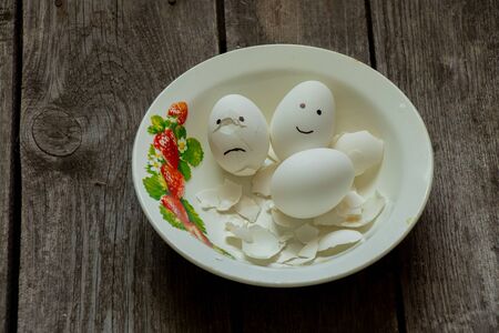 sad and joyful chicken egg in a plate in the shell