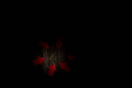 paper arrows pointing to the center of the table on a dark backgroundの写真素材