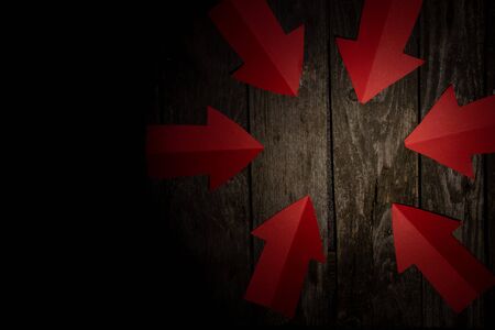 paper arrows pointing to the center of the table on a dark backgroundの写真素材