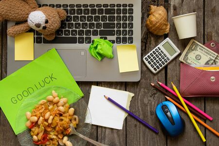 mess on the desktop laptop pencils and money paper and plate of food word in english luckの写真素材