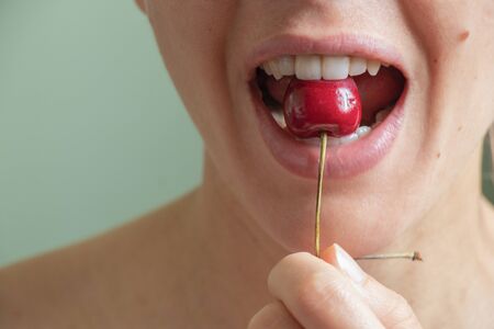 girl eats cherry close up on an isolated backgroundの写真素材