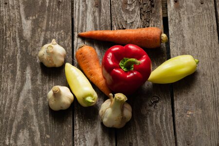 pepper carrots garlic from the vegetable garden lie on an old wooden tableの写真素材