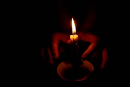 candle flame illuminates a female hand in a roomの写真素材