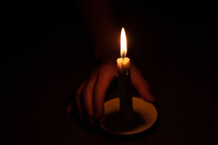 candle flame illuminates a female hand in a roomの写真素材