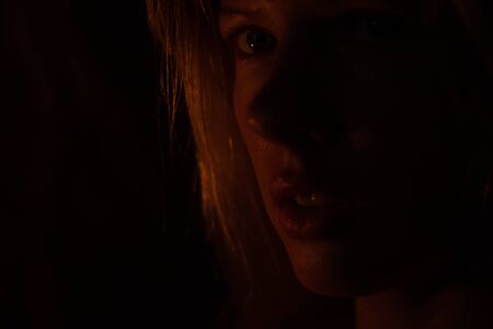 face of a young girl backlit by a candle on a dark background