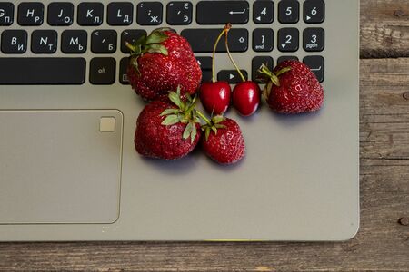 ripe strawberries and laptop on old wooden tableの写真素材