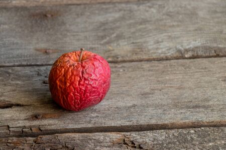rotten apple on a wooden table close-upの写真素材