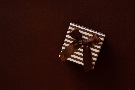 striped gift box stands on leather backgroundの写真素材
