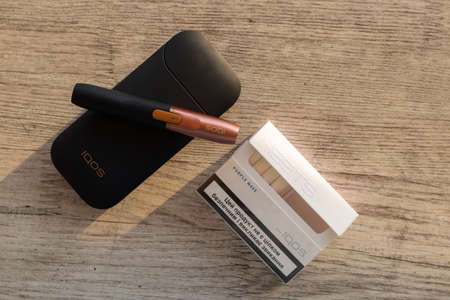 Ukraine, Dnipro - July 02, 2020. pack of cigarettes and iqos electronic cigarettes on a wooden table, addiction and bad habitsのeditorial素材