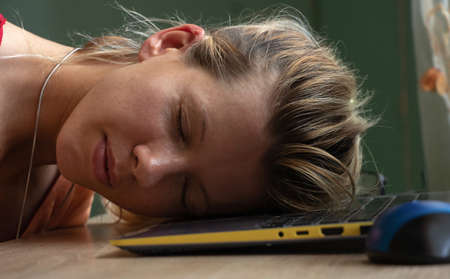 young Ukrainian girl sleeping at a workplace at a laptop at lunch breakの写真素材