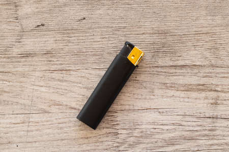 black lighter lies on a wooden table in daylightの写真素材