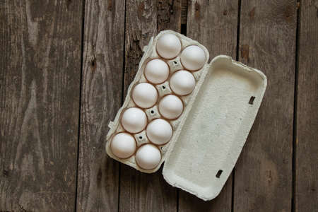 chicken eggs in a cardboard box on a wooden table in the kitchenの写真素材