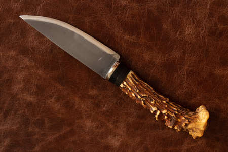 knife with a handle of a deer horn on a leather backgroundの写真素材
