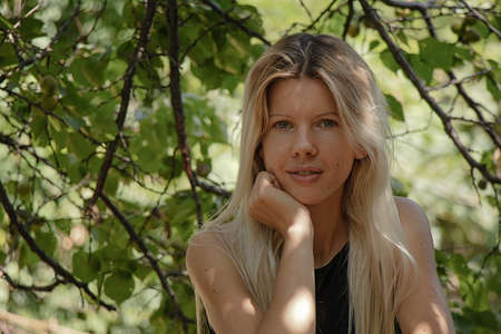 Ukrainian is sitting in a summer dress under a tree on a bench