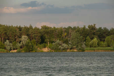 pine forest against the background of a blue lake in Ukraine in the city of dneprodzhezzzhinsk from a flooded quarryの写真素材