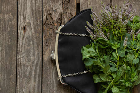 black black small bag and blooming mint on an old wooden tableの写真素材