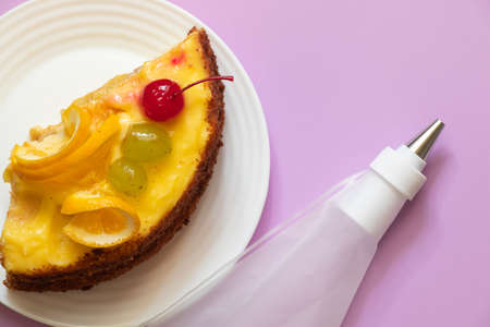 piece of fruit cake and pastry bag on colored background for birthdayの写真素材