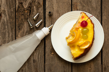 a piece of fruit cake and a pastry bag on a wooden table for birthdayの写真素材