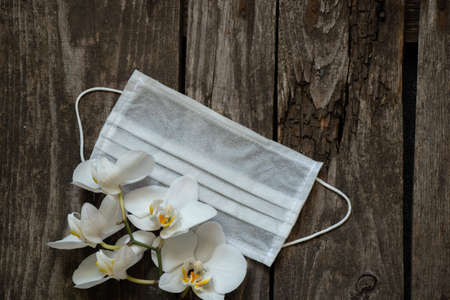 white medical mask and orchid flower on tableの写真素材