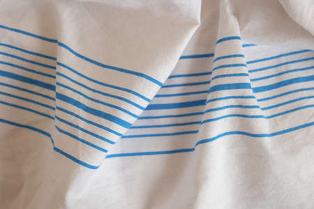 white fabric sheets in the hospital with blue stripes as background wrinkled