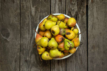 green homemade pear in a plate stands on a wooden table in the kitchen