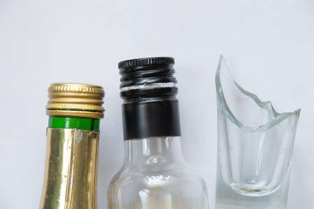 broken glass and empty bottle of alcoholic drink on white background, alcohol addictionの写真素材