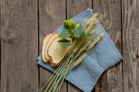 three pieces of white bread and grains of dry wheat from the field on a wooden table on the kitchen, baked goodsの写真素材
