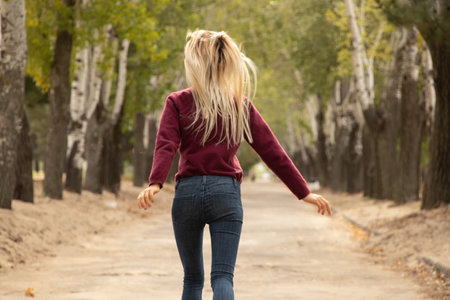 a girl runs along the road in an autumn park in ukraine in the city of dniproの写真素材