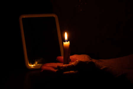 old woman's hands and candle flame in the dark, candle light, mourning, candle in the darkの写真素材