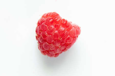 one red raspberry on a white background macro photo