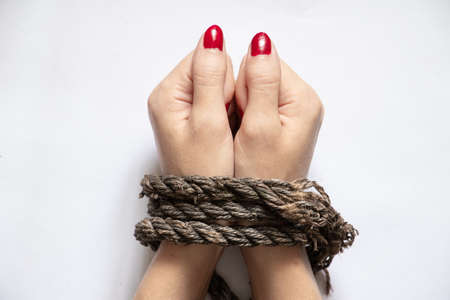 tied female hands with rope on white background close upの写真素材