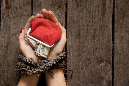 red wallet with American dollars in the girl's tied hands on the table