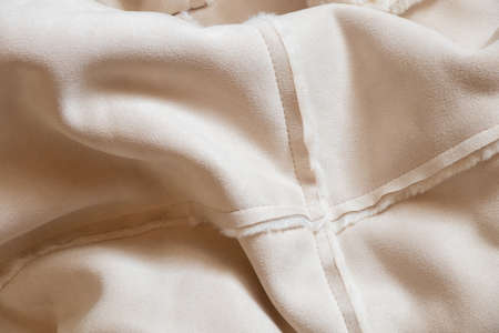 women's white sheepskin coat made of artificial materials as a background close-up