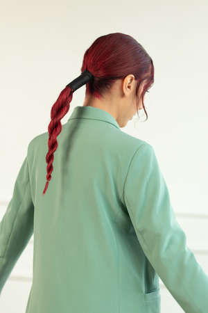 portrait of a young girl with red hair with makeup and in a green jacket and jtns in the studio, beauty fashionの写真素材