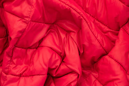 red fabric of a warm puffed jacket as a background close up