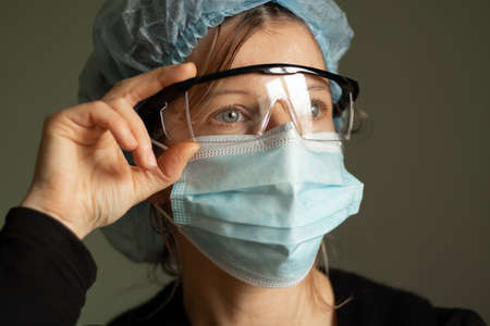 close-up portrait of a young Ukrainian girl in a medical cap, mask and glasses