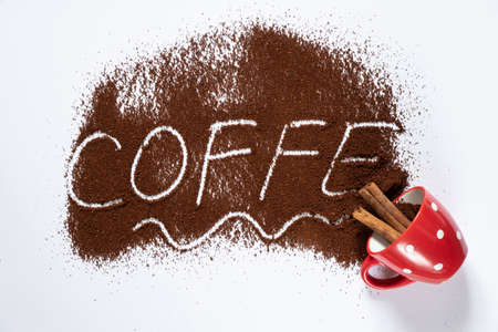 ground roasted coffee sprinkled on white background and white coffee cup close up close-upの写真素材