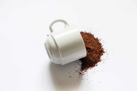 ground roasted coffee sprinkled on white background and white coffee cup close up close-upの写真素材